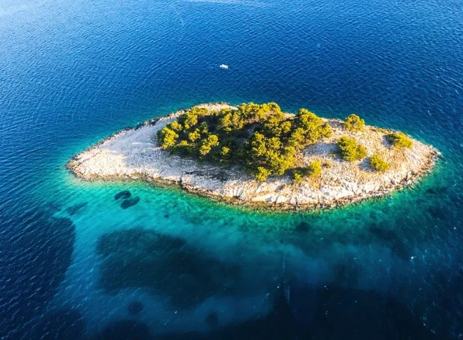 Eine kleine Insel im türkisblauen Meer, von oben fotografiert